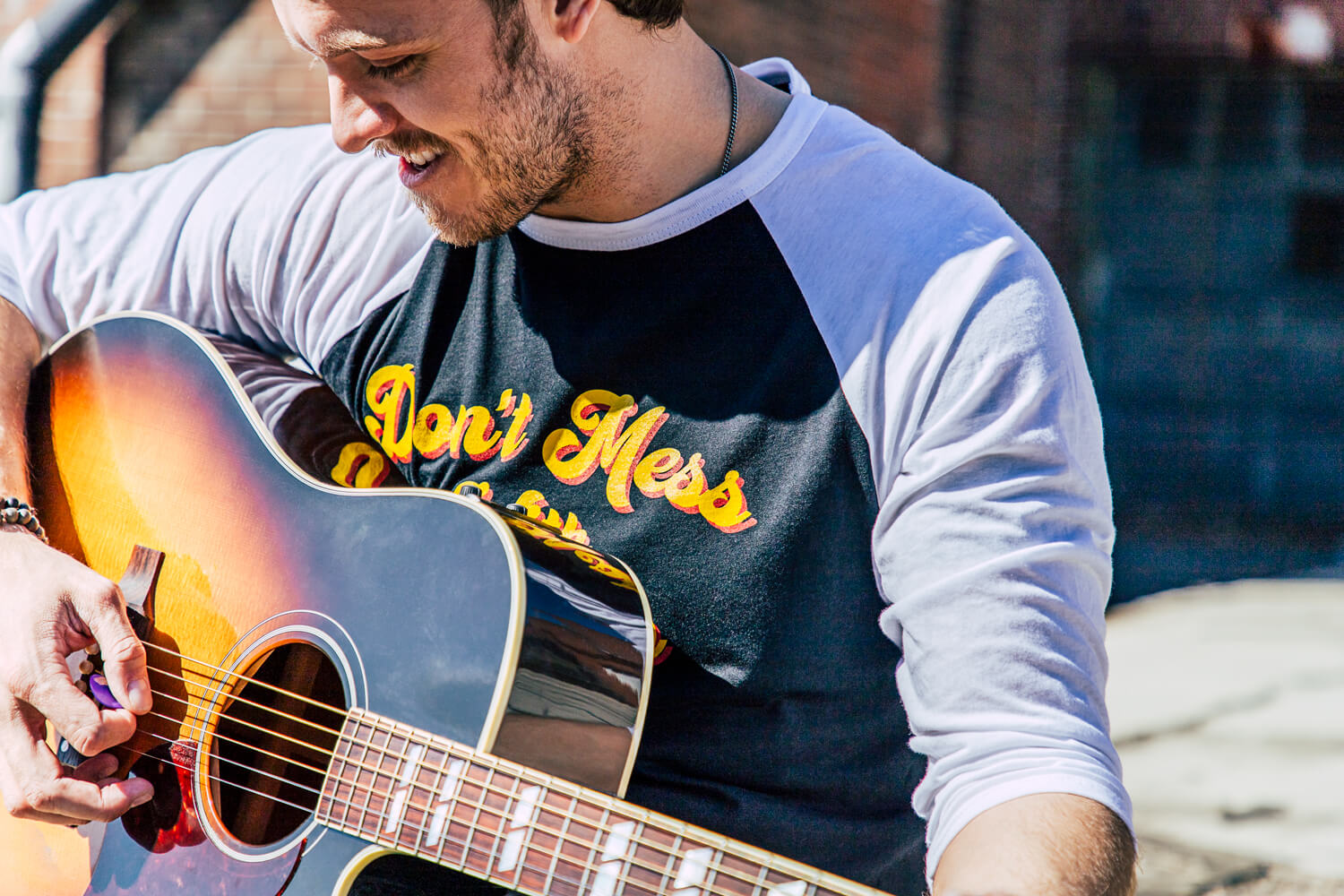 Man playing his guitar outside.