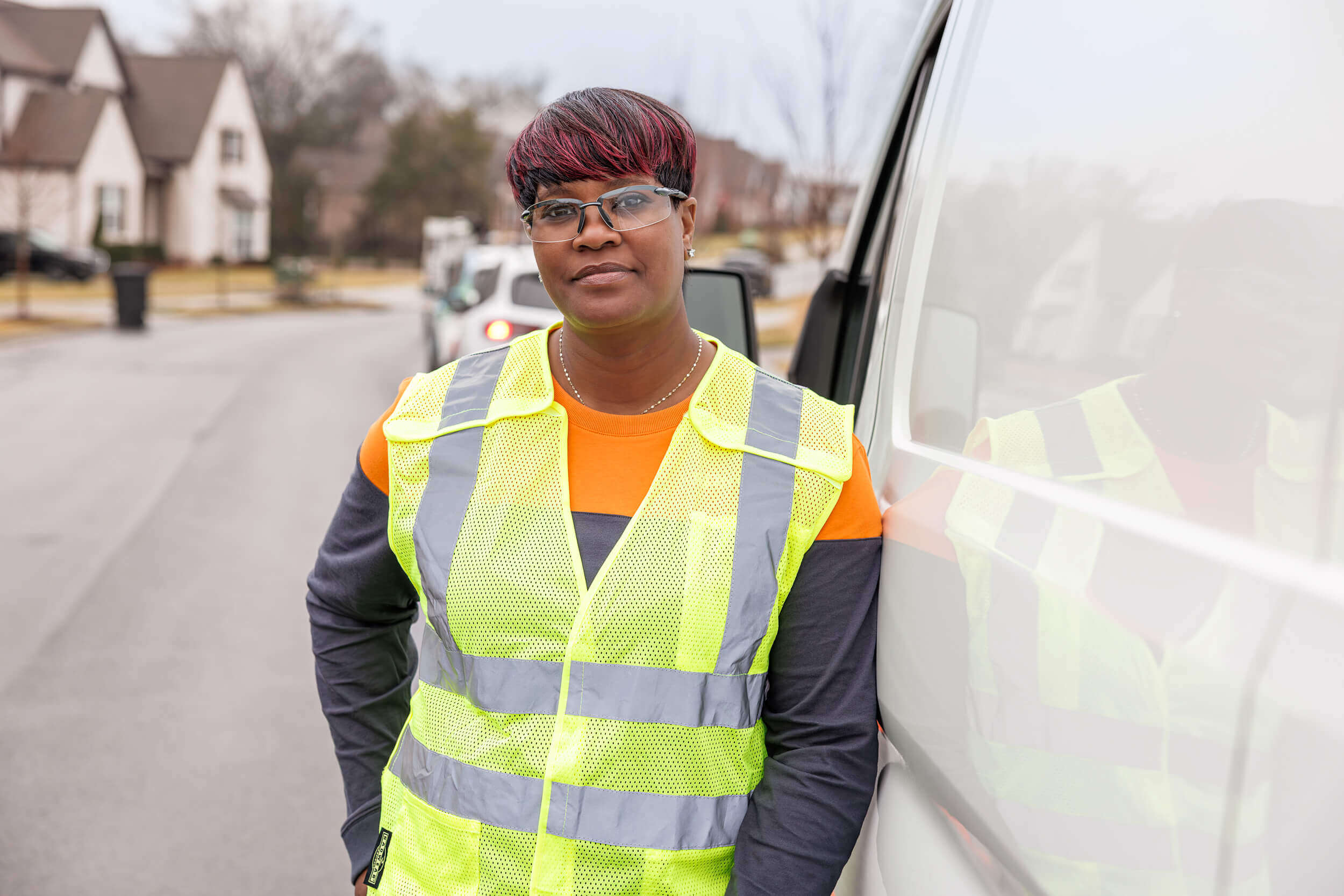 portrait of woman in safety gear leaning on van